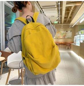 Detail of yellow corduroy backpack with adjustable straps and side drawstrings