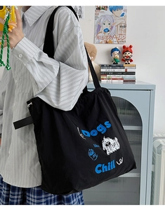 Detail view of black canvas tote bag with blue Dogs like Chill text and puppy graphic