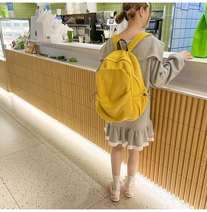 Ginger yellow corduroy backpack featured in a casual lifestyle cafe setting