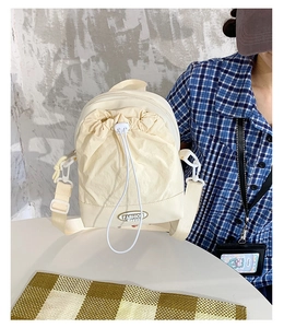 Detail view of cream white nylon crossbody bag with drawstring closure and logo patch