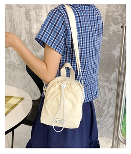 Detail of minimalist beige nylon drawstring crossbody bag with Fashion Happy logo patch