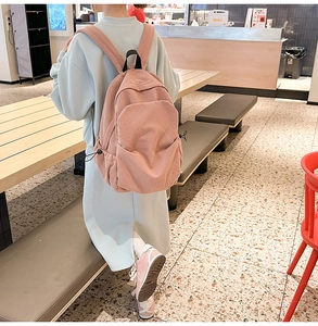 Detailed view of pink corduroy backpack featuring side drawstring pockets and padded straps