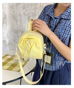 Detail of yellow nylon crossbody bag featuring white drawstring pocket and fashion badge