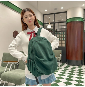 Detail of dark green corduroy backpack showing vertical texture and side drawstring
