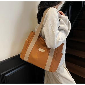 Dettaglio di una grande borsa tote in tela marrone con spalline beige e tasca laterale