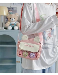 Detailed side view of pink and white canvas crossbody bag with bunny ears and badges