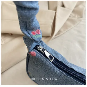 Close-up of floral denim underarm bag featuring a smooth silver zipper and ruffle handle