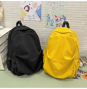 Close-up of textured corduroy backpacks in black and yellow showing side drawstring pockets