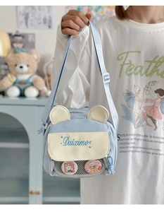 Detail of light blue canvas crossbody bag with beige ears and cute rabbit badges