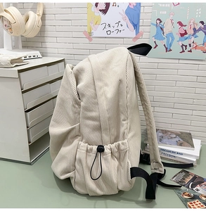 Detail of corduroy backpack showing side drawstring pocket and black canvas strap
