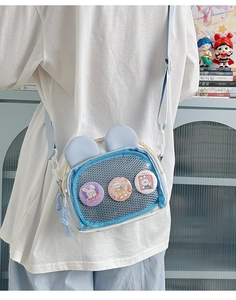 Détail du sac ita bleu clair avec oreilles de lapin et fenêtre affichant des badges