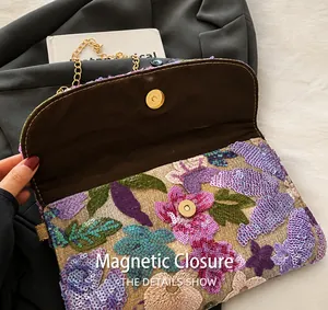 Detail van het bloemenborduurwerk, pailletten en magnetische sluiting van de handtas