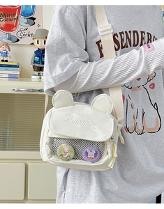 Detail of white canvas crossbody bag featuring animal ears and character badges