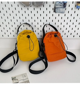 Detalle de bolsos tipo cubo de nailon amarillo y naranja con cordón y correa ajustable