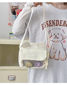 Detail of cute cream crossbody bag with bear ears, mesh pocket and rabbit badges