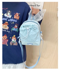 Detail view of light blue nylon crossbody bag featuring drawstring closure and shoulder strap