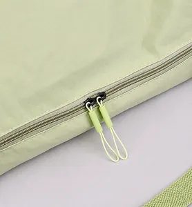 Detail of light green gym bag featuring durable dual zippers with long cord pullers