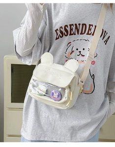 Detail of cute beige canvas shoulder bag with bear ears, clear pocket and pins on a model
