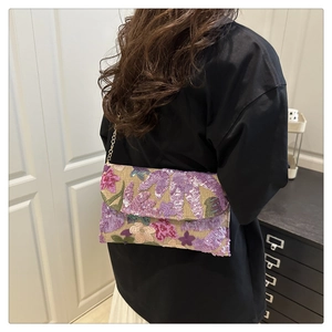 Detailed view of floral sequin embroidery on clutch bag with golden metal chain