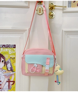 Dettaglio della borsa rosa e blu con logo a cuore e ciondolo a forma di luna gialla