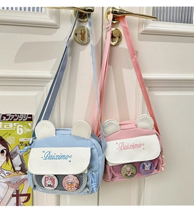 Detail of cute rabbit ear crossbody bags with mesh pockets and cartoon badges on a door