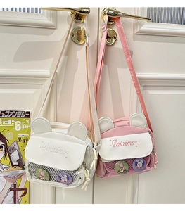 Close-up of cute bear-eared crossbody bags in white and pink with mesh pocket and badges