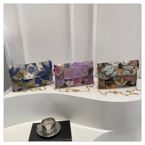 Detail van bloemenborduurwerk met pailletten op clutch-tassen met gouden ketting