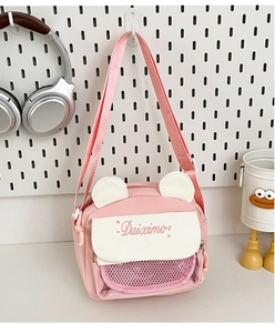 Detail of pink canvas ita bag with white bear ears and a mesh pocket on a display board