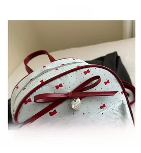 Detail van rood polka dot patroon met lederen strik en hartvormige hanger op blauwe rugzak