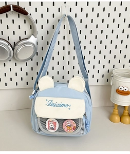 Detail of light blue crossbody bag with bear ears and clear grid pocket for badges