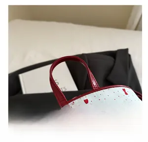 Detail van rood lakleren handvat en metalen rits op de rugzak met rode stippen