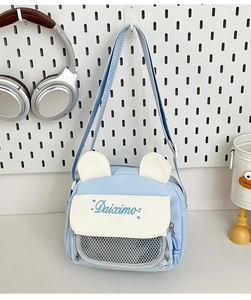Close-up of a light blue cute crossbody bag with white ears and a mesh pocket detail