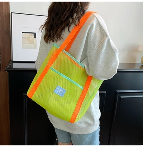 Detailed view of neon green mesh beach bag with orange straps worn on shoulder