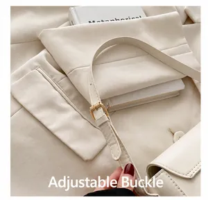 Close-up of golden adjustable buckle on cream leather shoulder strap of a handbag