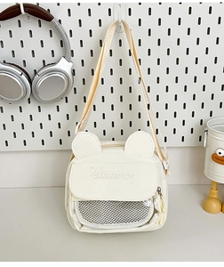 Detail of white cartoon shoulder bag with cute ears and a transparent mesh pocket