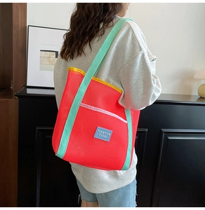 Detail of red mesh beach bag with green shoulder straps and large storage capacity