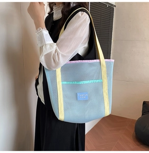 Detail of light blue mesh beach bag with yellow handles and large storage pocket