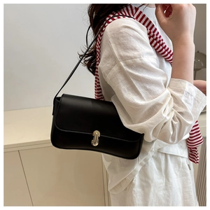 Detail shot of a minimalist black leather underarm bag with a gold buckle on model