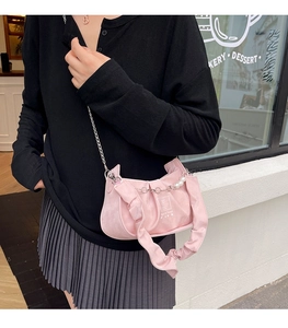 Detail of pink pleated cloud bag with white pearl chain strap and silver metal link