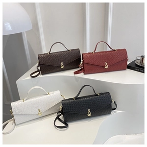 Dettaglio di quattro borse intrecciate in marrone, rosso, bianco e nero con finiture oro