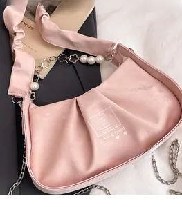 Detailed view of pink pleated cloud bag featuring pearl flower chain and bear logo design