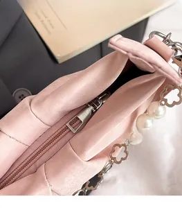 Detail of pink pleated cloud bag featuring pearl chain and floral metal hardware accents