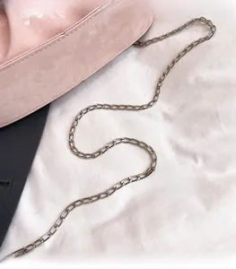 Detailed close-up of the light gold metal chain on a pink matte suede crossbody bag