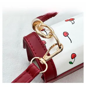 Detailed close-up of cherry pattern on white faux leather with red woven handle