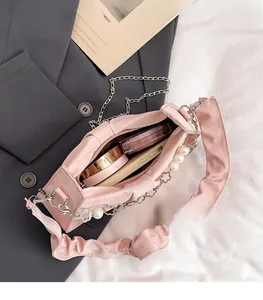 Detailed view of pink pleated bag with pearl charm, metal chain and spacious interior