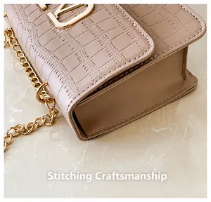 Detalle del bolso rosa nude con patrón de cocodrilo, logo dorado y costuras finas