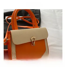 Detail of straw woven crossbody bag with orange leather trim and golden metal clasp