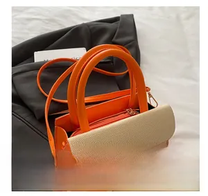 Detail of orange leather handbag with beige woven flap and circular handle