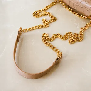 Detalle de bolso beige de piel de cocodrilo con correa de cadena de metal dorado