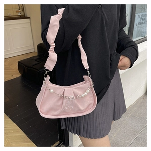 Detail of pink pleated cloud bag featuring pearl chain and floral metal accents
